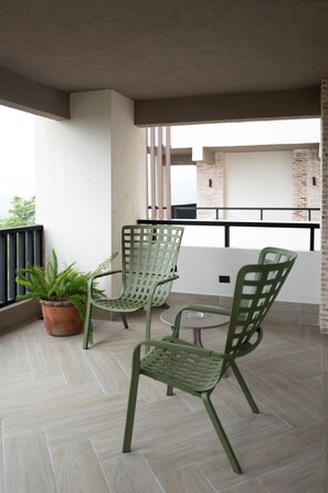 A balcony with two green chairs and a potted plant. - Camp David Ranch (Santiago de los Caballeros)