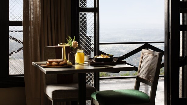 A dining table with breakfast items, a chair, and a view of the landscape through large windows. - Camp David Ranch (Santiago de los Caballeros)