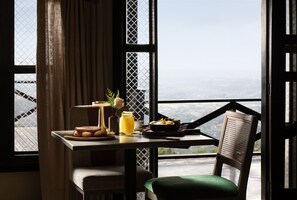 A dining table with breakfast items, a chair, and a view of the landscape through large windows. - Camp David Ranch (Santiago de los Caballeros)