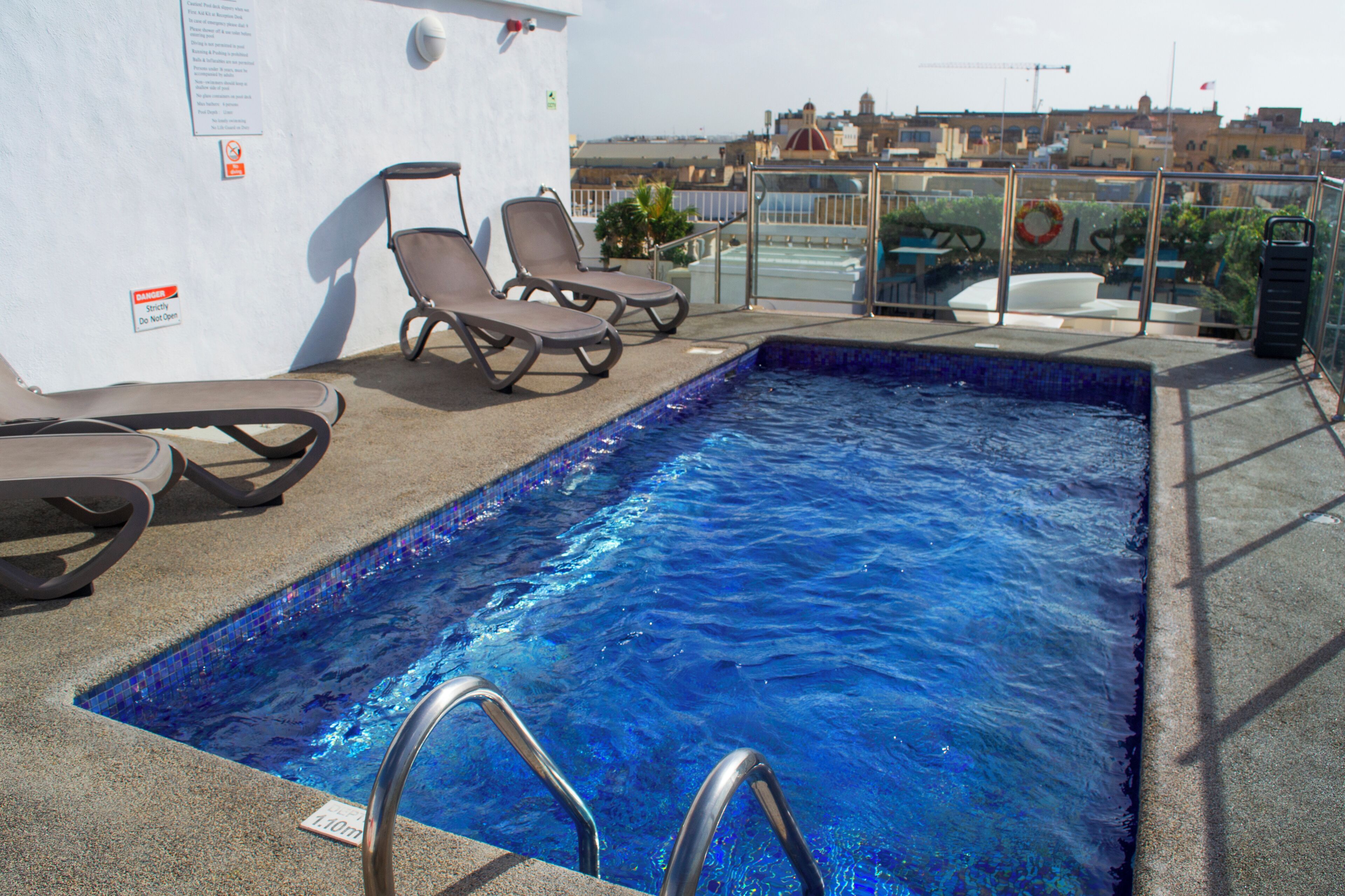 Una piscina al aire libre, sillones reclinables de piscina