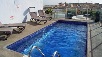 Una piscina al aire libre, sillones reclinables de piscina