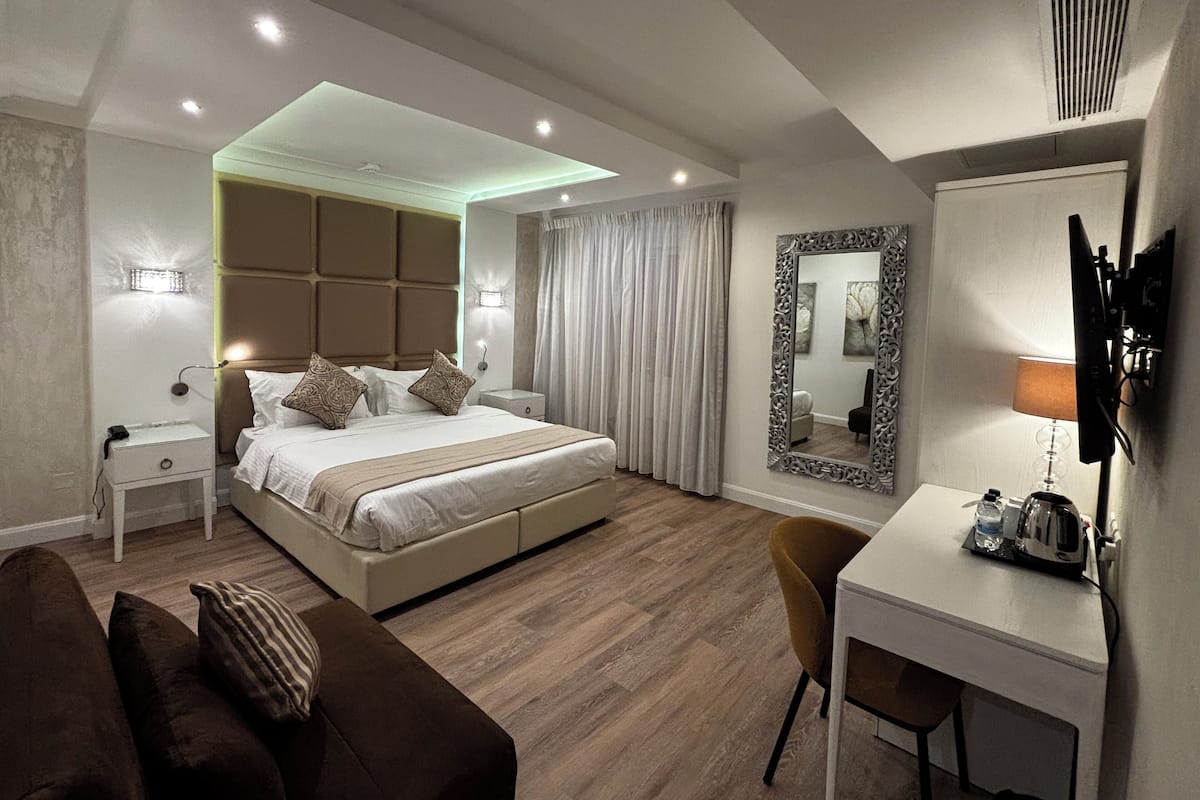 A modern hotel room with a large bed, a desk, a chair, and a TV.