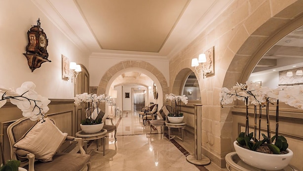 Eine luxuriöse Lobby mit aufwendigen Möbeln, weißen Orchideen und einer klassischen Uhr.