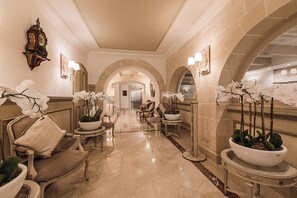 A luxurious lobby with ornate furniture, white orchids, and a classic clock. - Osborne (Valletta)