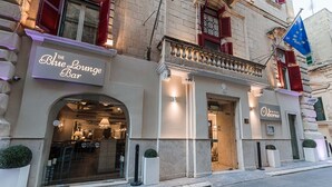 Die Blue Lounge Bar mit moderner Fassade, einem gut sichtbaren Eingang und einer Flagge, die einen europäischen Standort kennzeichnet.
