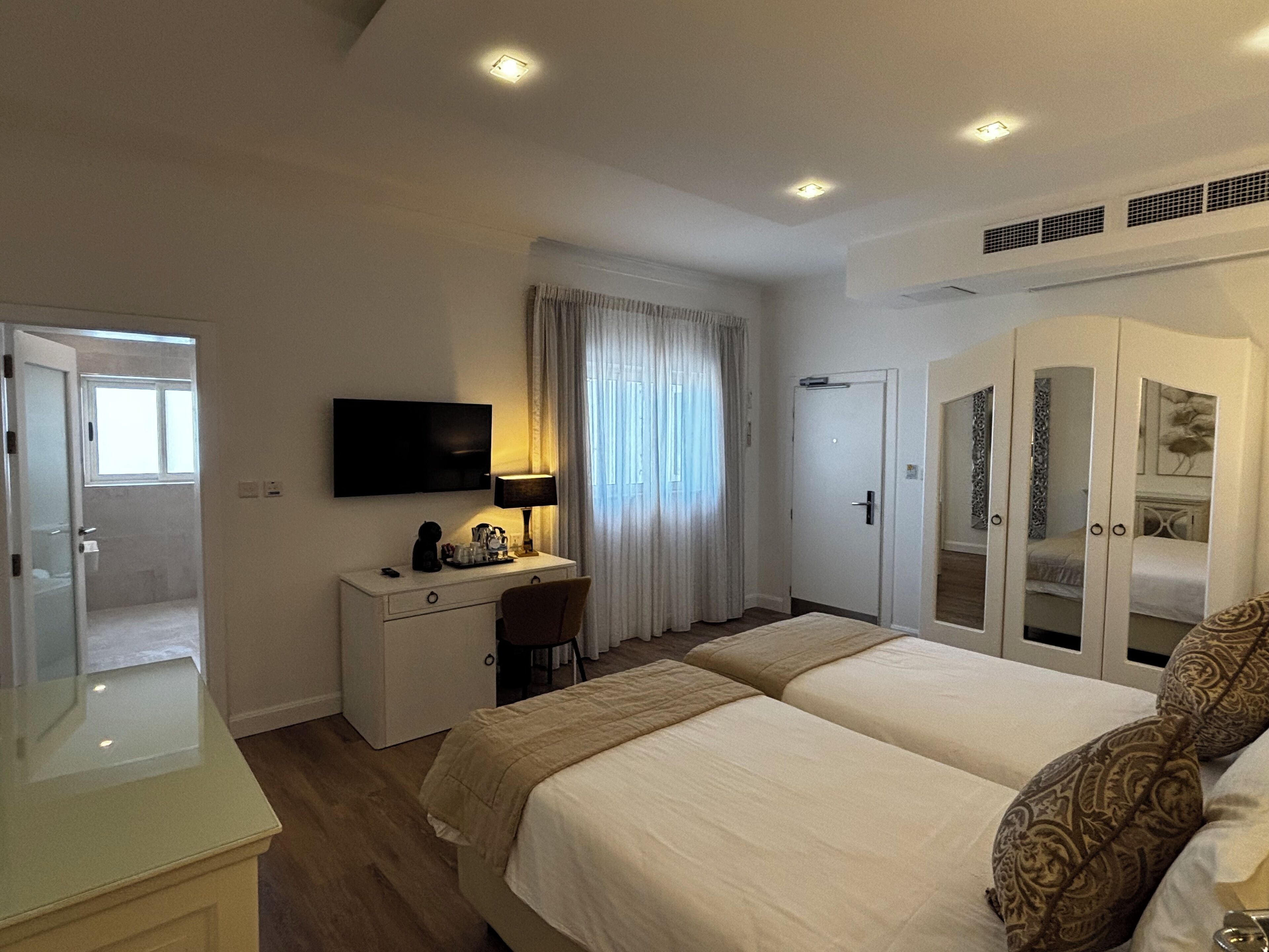 Una camera d'albergo con un letto, una scrivania con una sedia, una televisione e un armadio.