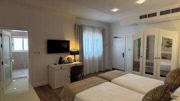 Una camera d'albergo con un letto, una scrivania con una sedia, una televisione e un armadio.