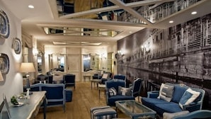 Ein geräumiges Wohnzimmer mit blau gepolsterten Möbeln, einem Couchtisch und einem gemusterten Teppich.