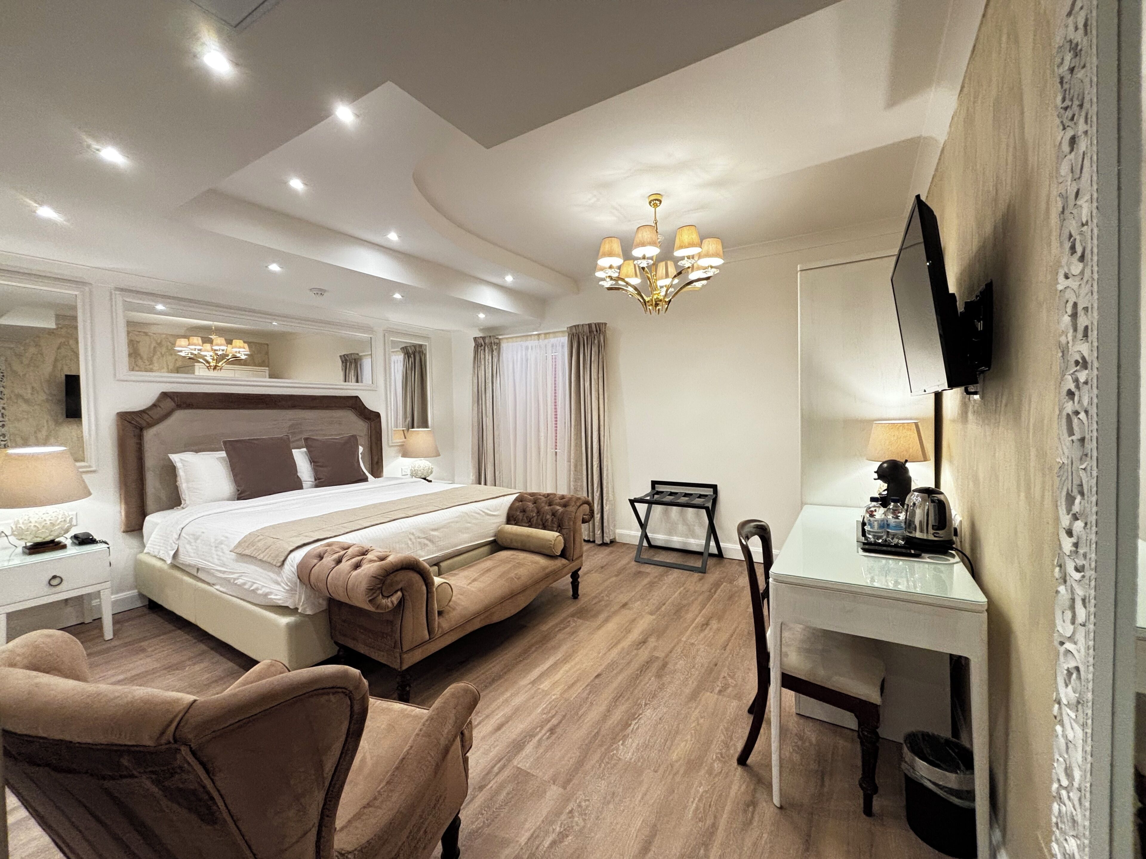 Una habitación de hotel moderna con una cama grande, un escritorio, una silla, un televisor y una araña.