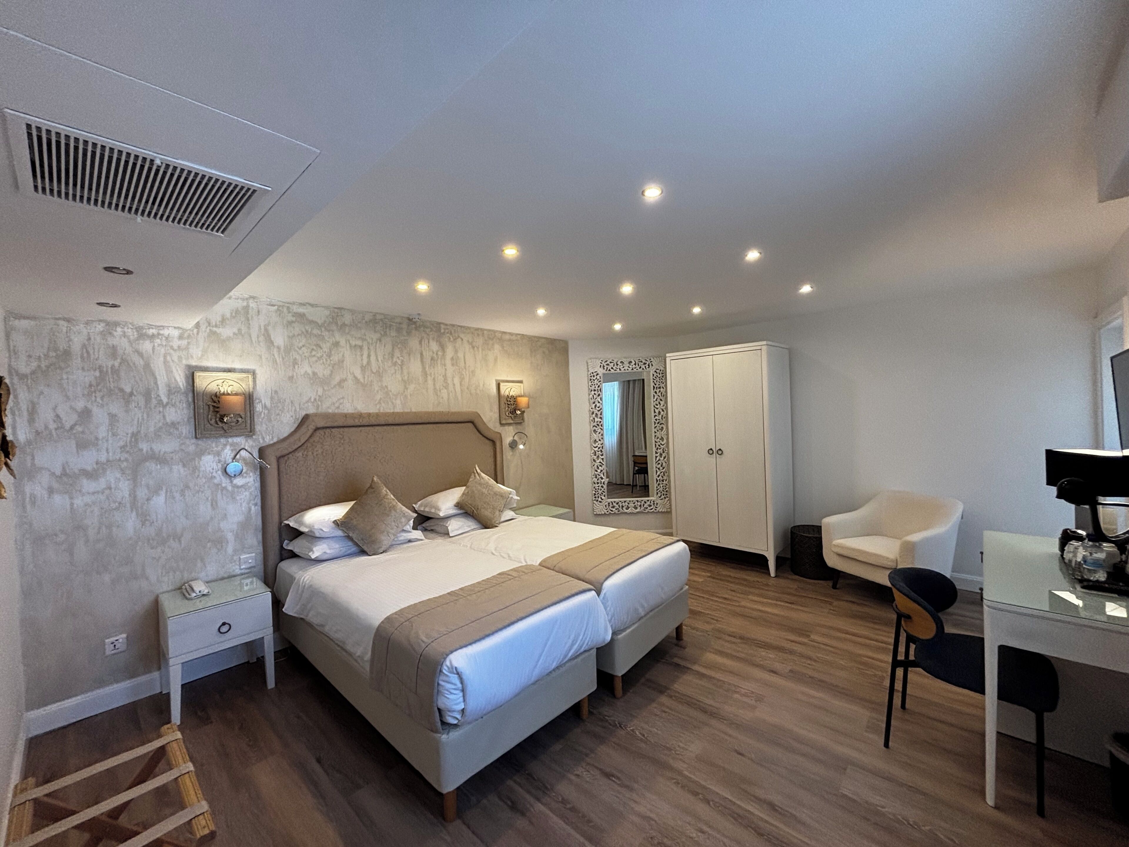 Una camera da letto con un letto matrimoniale, comodini, un armadio, una scrivania con una sedia e uno specchio.