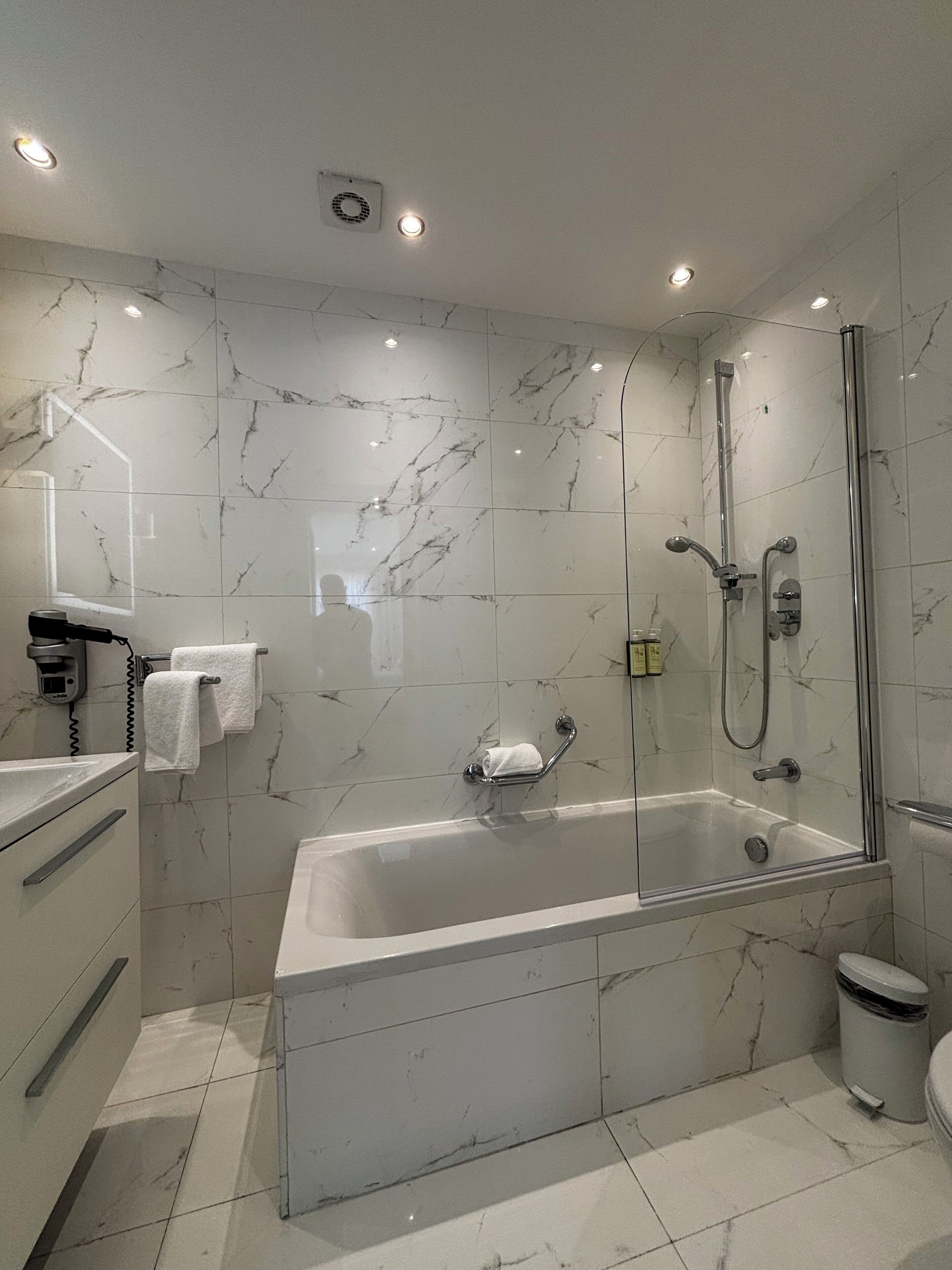 A modern bathroom with a glass-enclosed shower, a standalone bathtub, and a toilet.