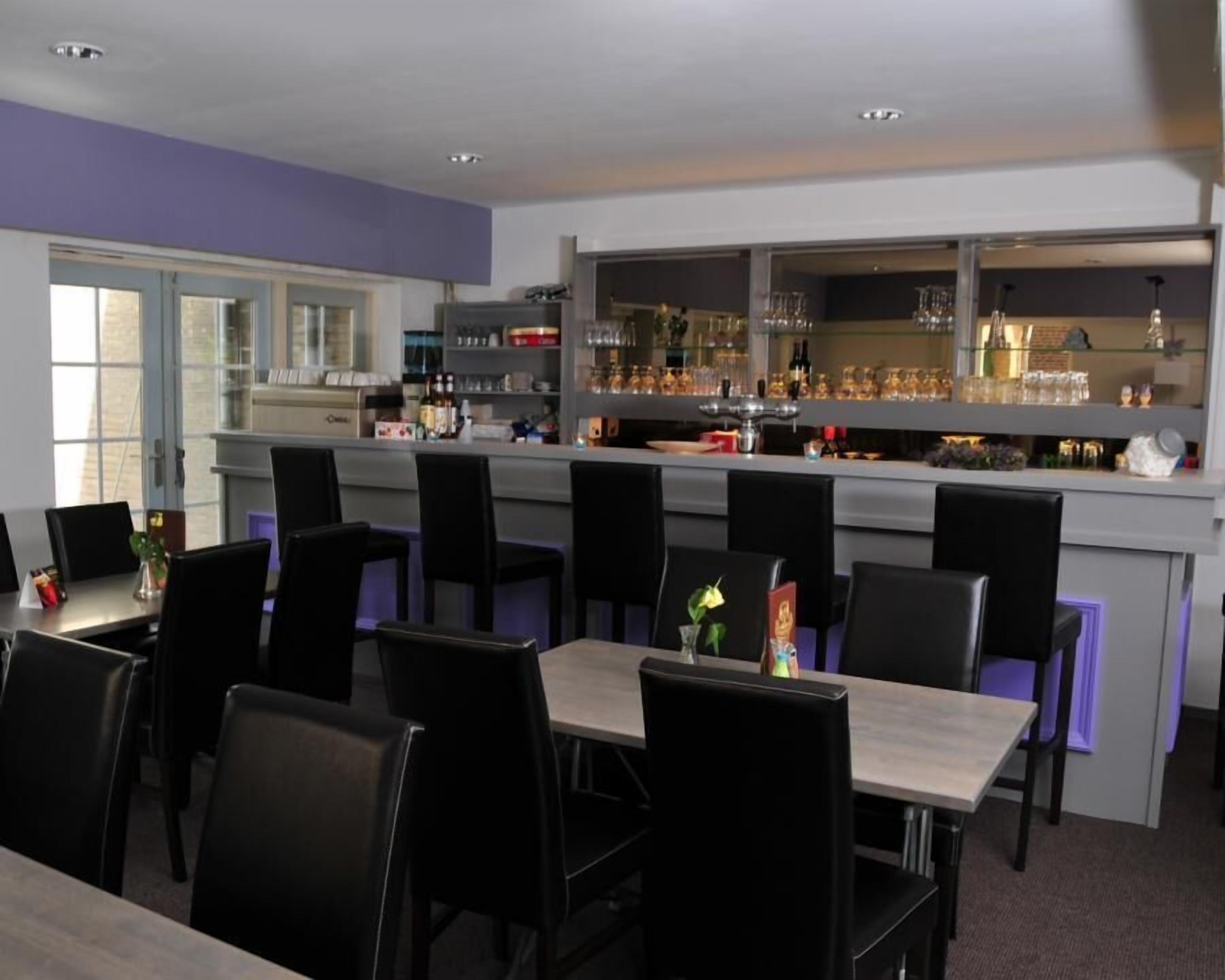 A restaurant with a bar area, multiple tables, and chairs.