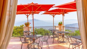 A terrace with tables and chairs, red umbrellas, and potted plants. - Grand Hotel Hermitage & Villa Romita (Massa Lubrense)