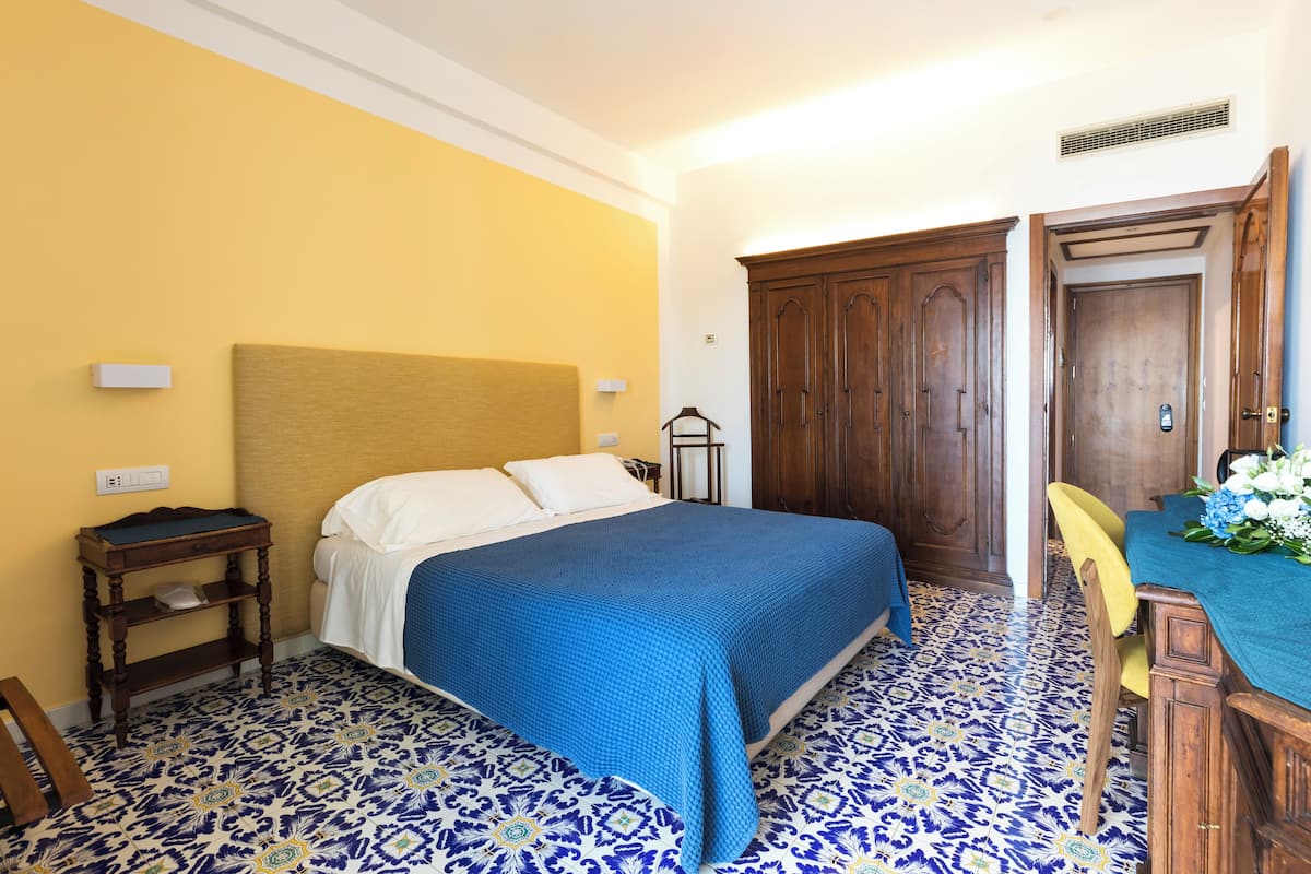 Ein Hotelzimmer mit einem Bett, einem Holzschrank, einem kleinen Tisch und einem Sessel.