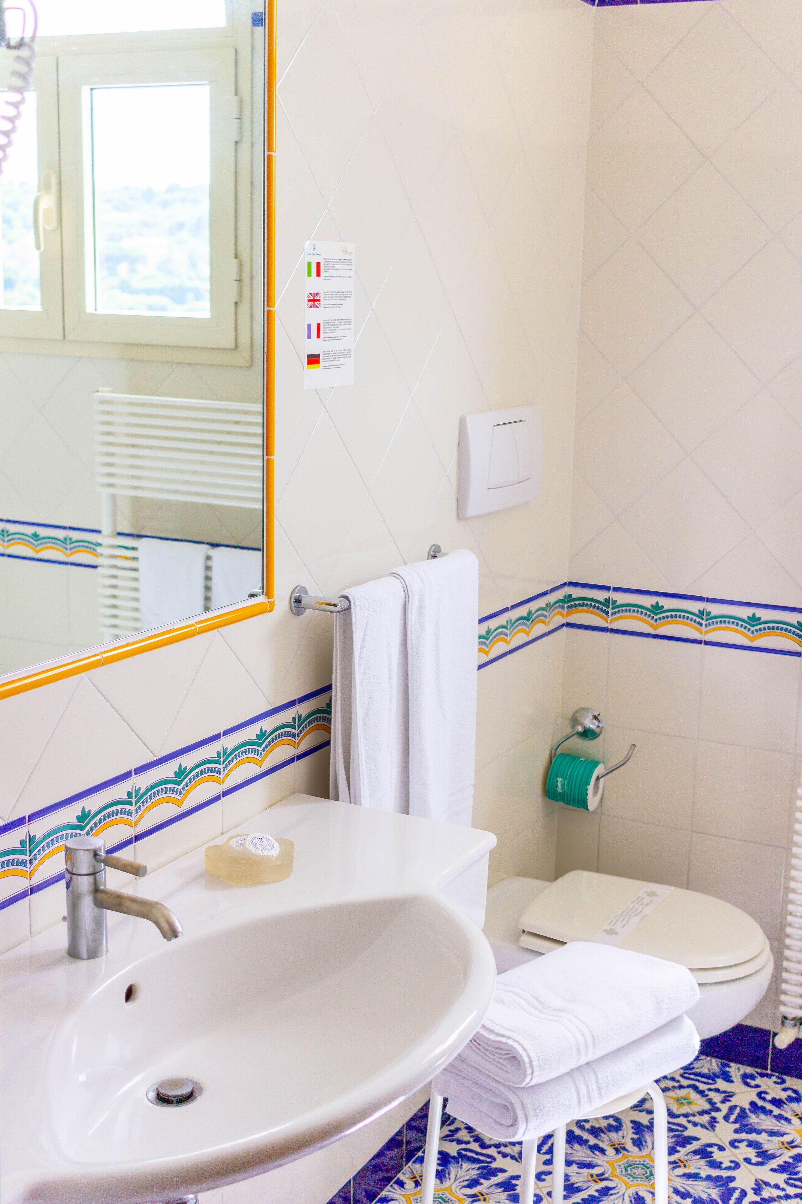 A bathroom with a white sink, a mirror, a towel rack, and a toilet.