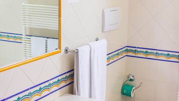 A bathroom with a white sink, a mirror, a towel rack, and a toilet.