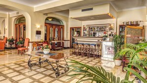 A spacious lobby with a checkered floor, a bar area with stools, and a piano. - Grand Hotel Hermitage & Villa Romita (Massa Lubrense)