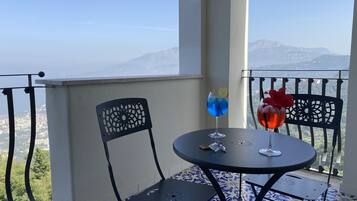 Un balcone con tavolo e due sedie, vista su un paesaggio montuoso.