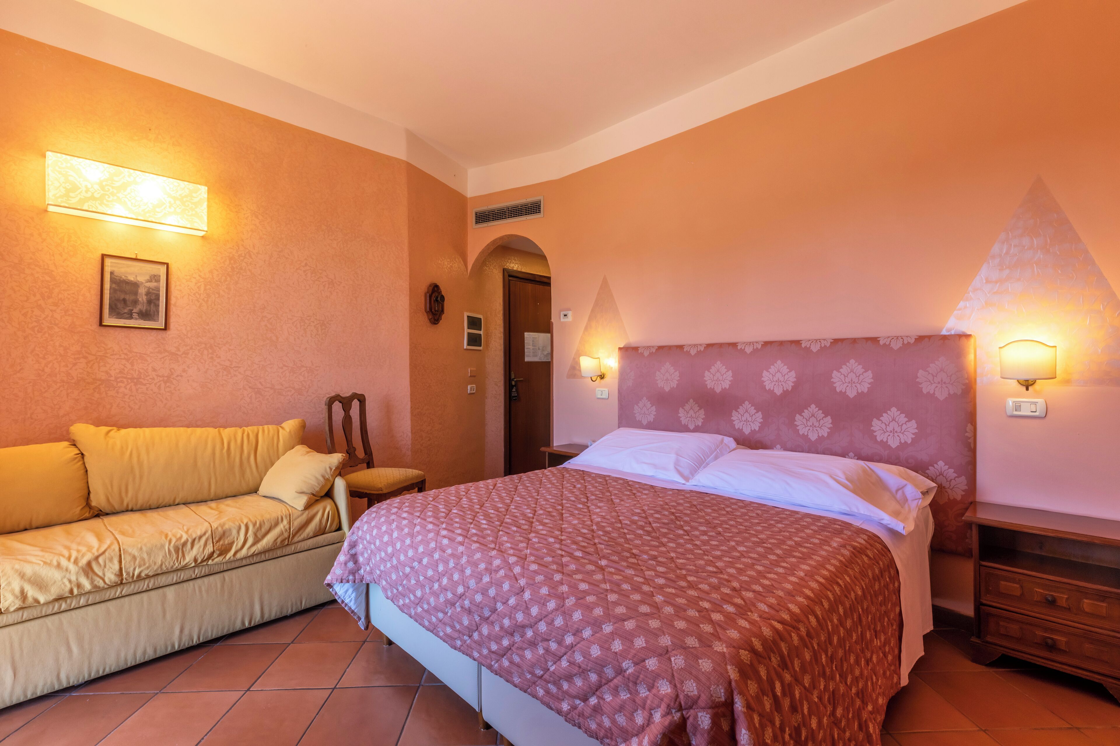 Un dormitorio con cama, sofá y mesita de noche.