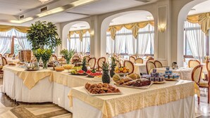 A banquet hall with multiple tables set for a buffet, featuring a variety of food items and a large potted plant. - Grand Hotel Hermitage & Villa Romita (Massa Lubrense)