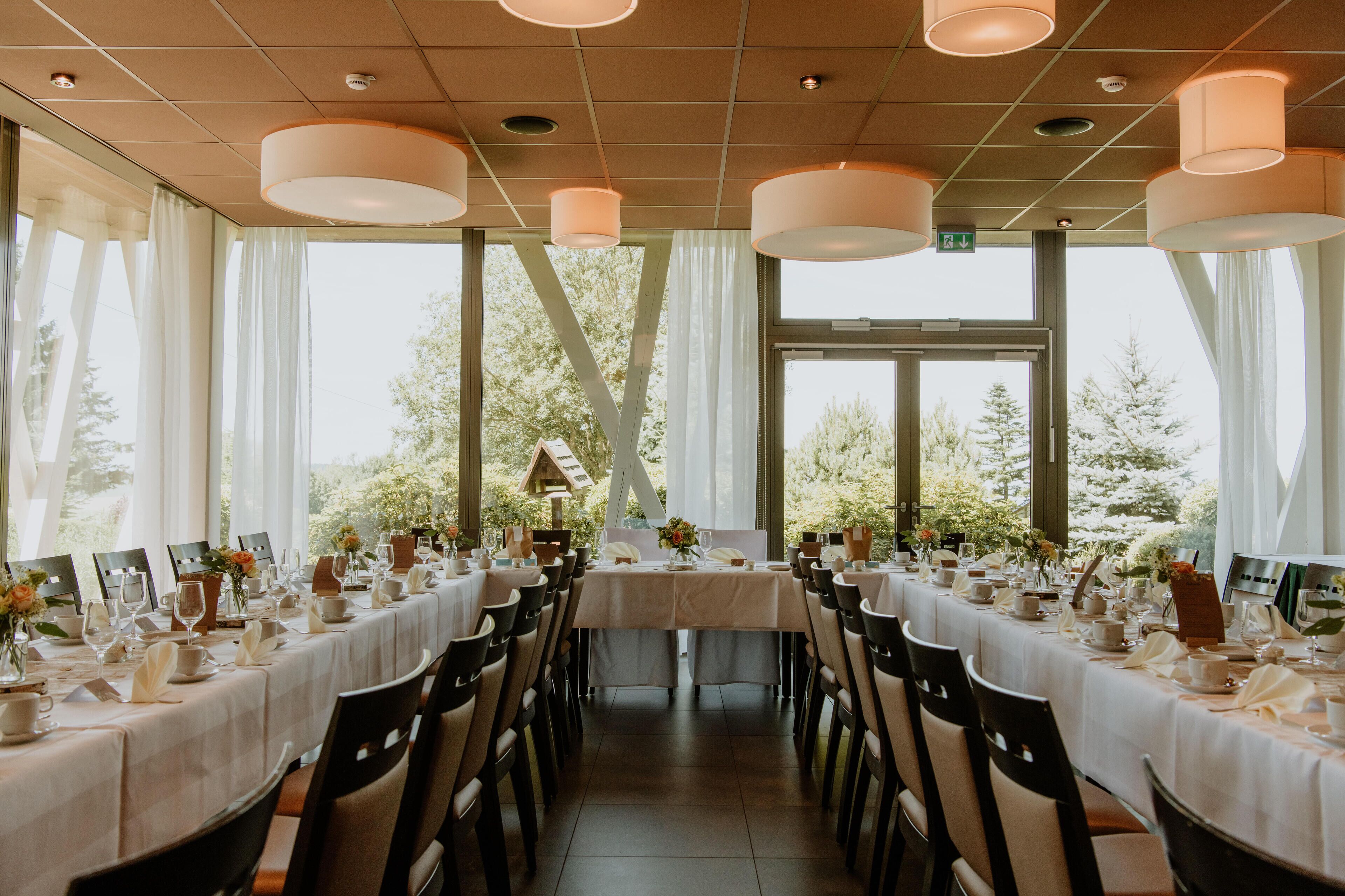A long dining table set for a formal event with chairs, candles, and floral centerpieces.