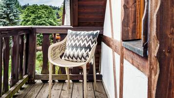 Une terrasse en bois avec une chaise en osier et un coussin à motifs en zigzag.