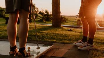 A person standing on a putting green at a golf course, holding a golf club.