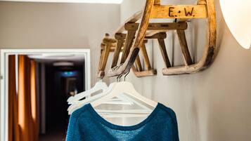 Un perchero de madera con las letras "E.W." grabadas, sosteniendo varios ganchos blancos con ropa.