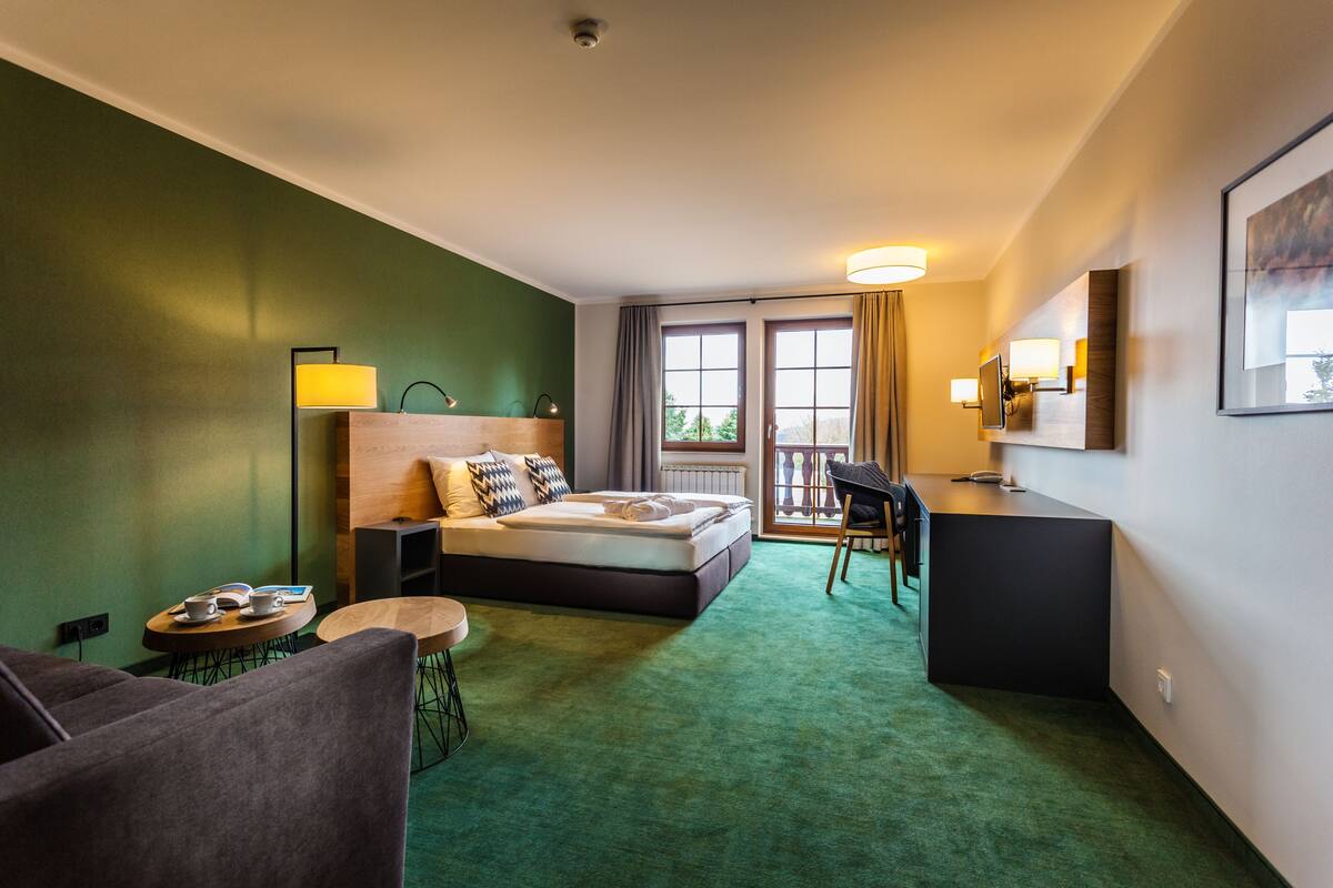 Een hotelkamer met een bed, een bureau, een stoel, een klein rond tafeltje en een bank.