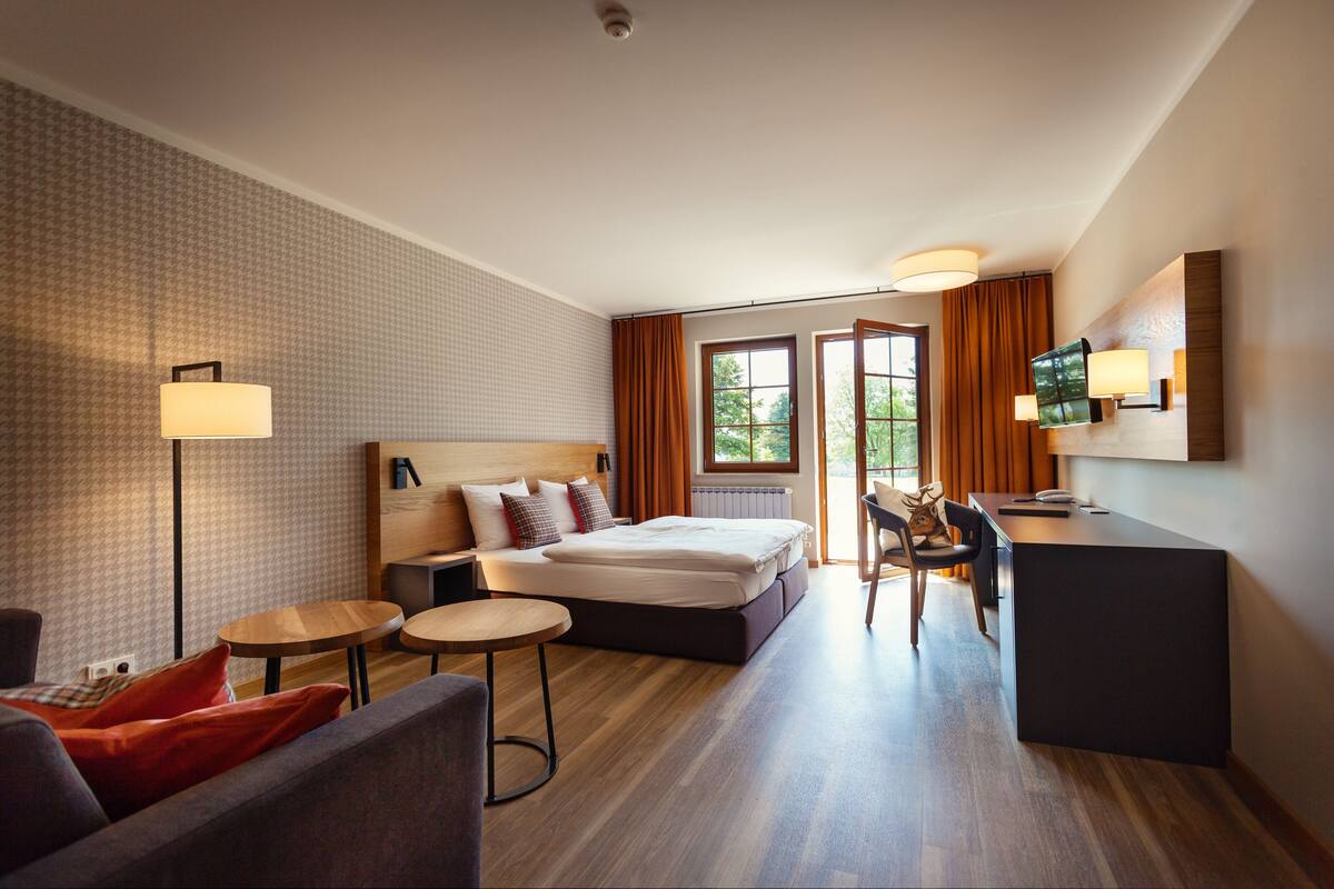 Een moderne hotelkamer met een bed, een bureau, een stoel, een bank en een televisie.