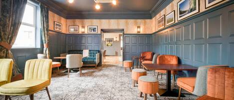 A room with a patterned floor, a sofa, multiple chairs, a table, and framed pictures on the wall.