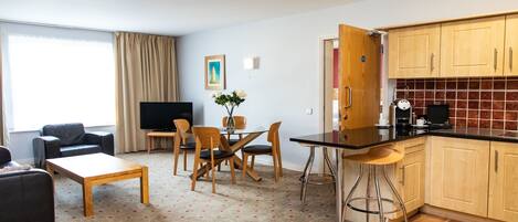Una sala moderna con sofá, televisor y comedor con sillas y una mesa.