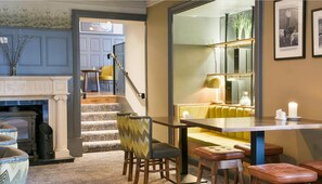 Un interior moderno con una escalera que conduce a un comedor, una chimenea y un banco de asientos.