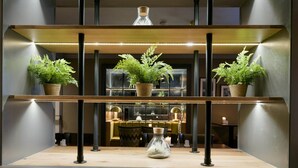 Een modern interieur met een houten plank waarop planten in potten en een glazen vaas staan.