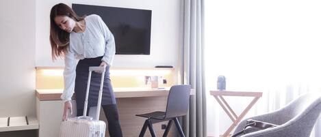 Een hotelkamer met een bed, een bureau, een televisie en een stoel.