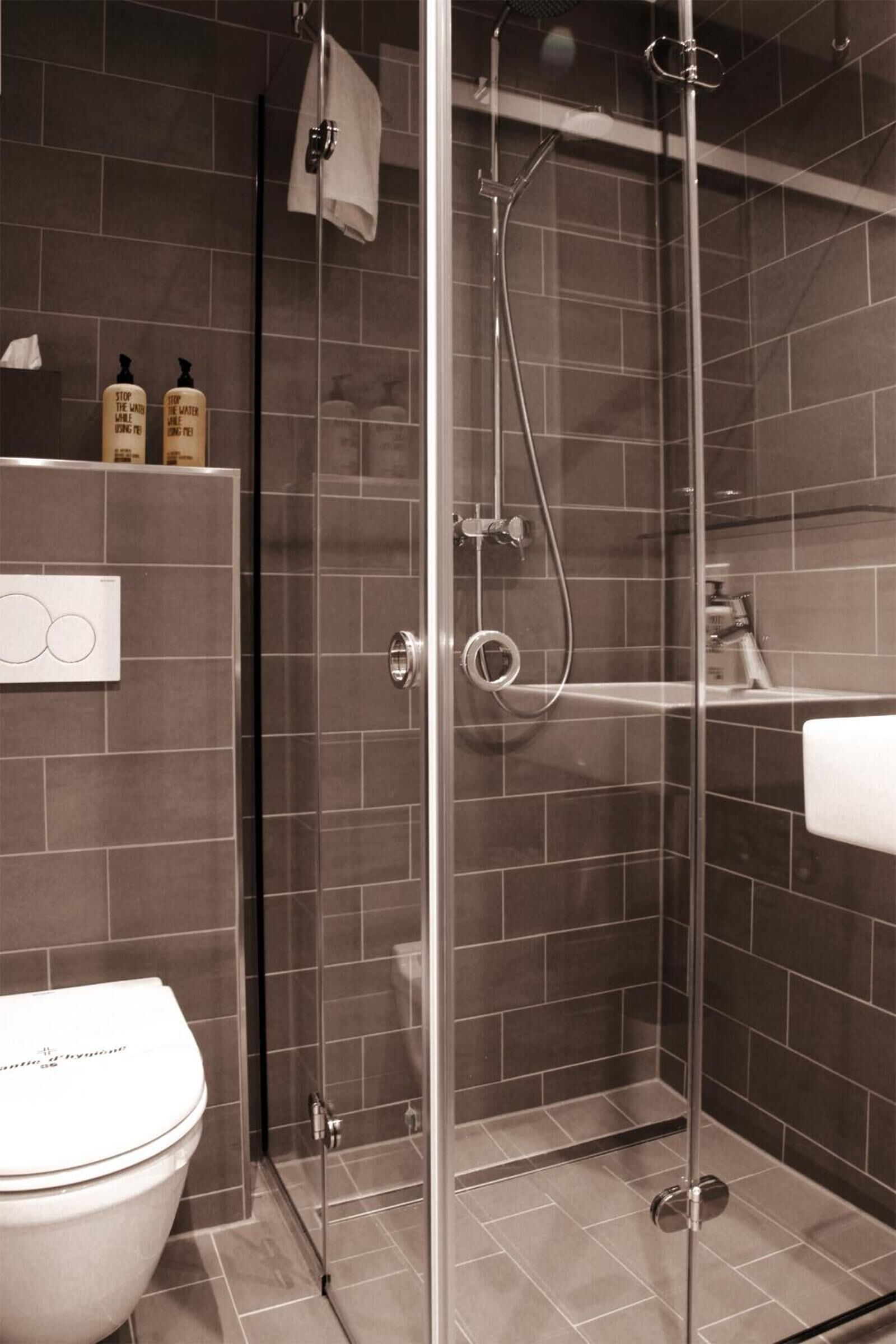 A modern bathroom with a glass-enclosed shower, a toilet, and a sink.
