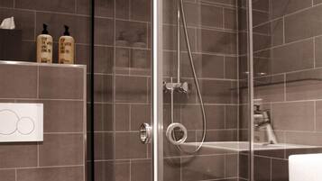 A modern bathroom with a glass-enclosed shower, a toilet, and a sink.