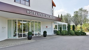A modern hotel entrance with a clear glass facade, a sign reading "HOTEL STADT BALINGEN", and well-maintained landscaping. - Hotel Stadt Balingen (Balingen)