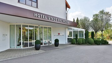 Una entrada de hotel moderna con fachada de vidrio transparente, un cartel que dice