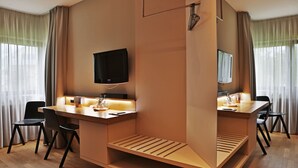 A modern hotel room with a wooden desk, two chairs, a flat-screen TV, and a large mirror. - Hotel Stadt Balingen (Balingen)