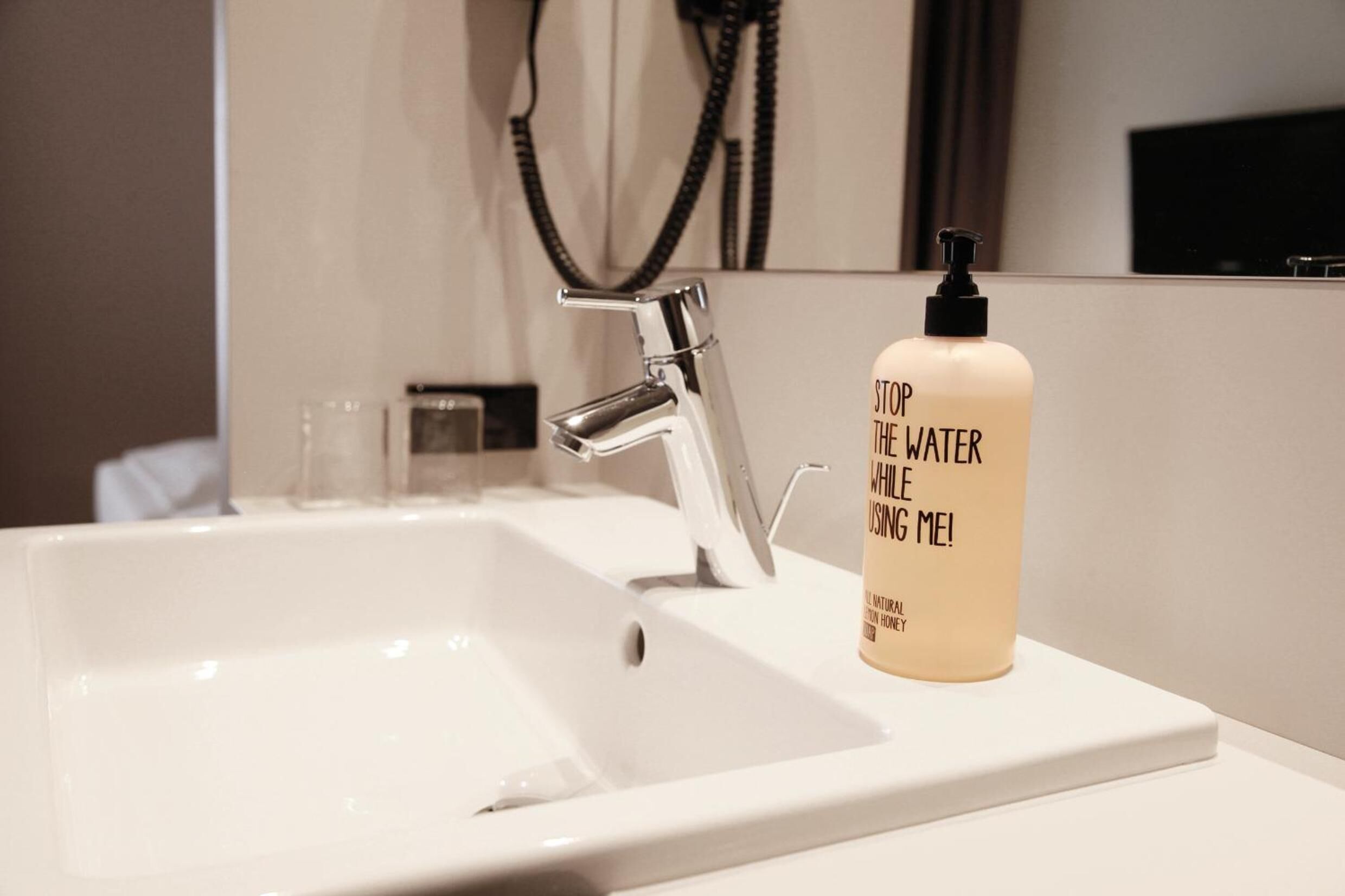 A bathroom sink with a modern faucet and a bottle of soap.