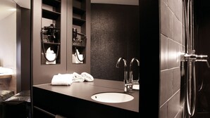 A modern bathroom with a dark countertop, a large mirror, a sink, and a shower area. - Hotel Stadt Balingen (Balingen)
