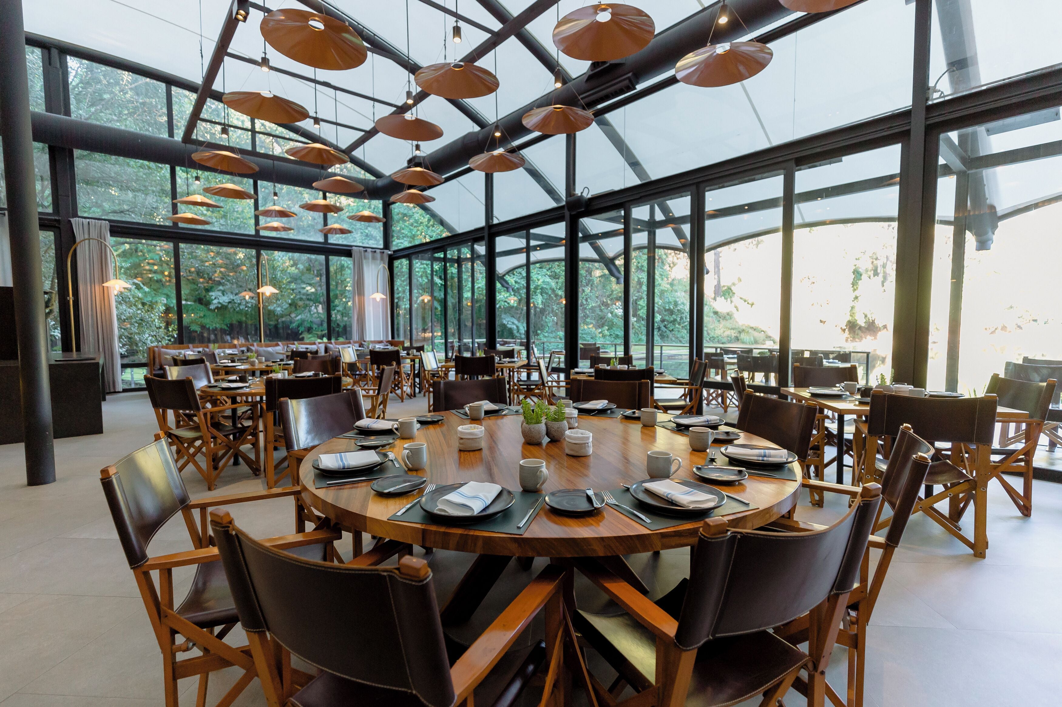 A spacious indoor dining area with round tables, chairs, and pendant lighting.