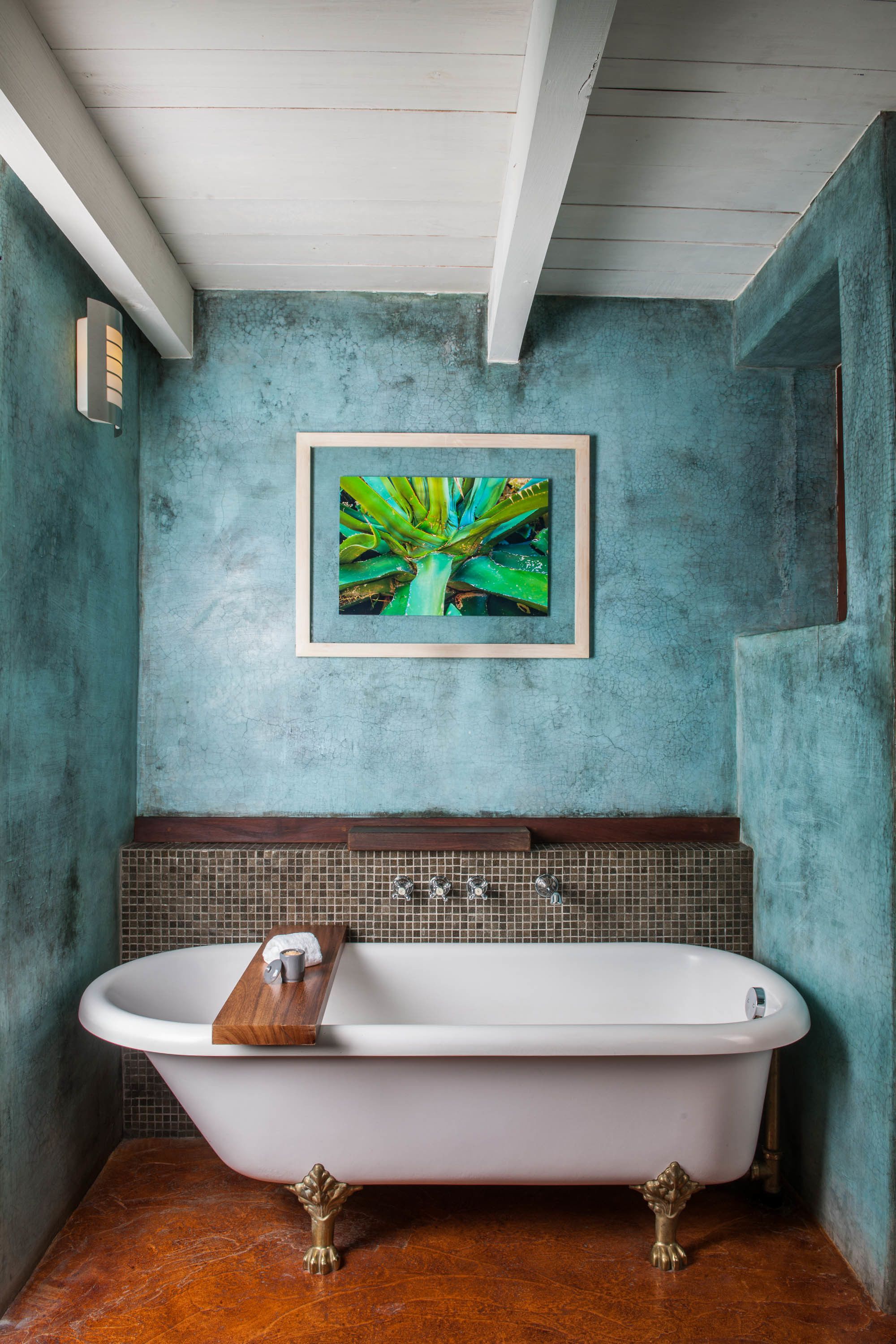 A bathroom with a freestanding bathtub, a framed botanical print on the wall, and a tiled backsplash.