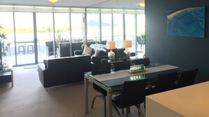 A modern dining area with a glass table, black chairs, and a view of the outdoors. - Cairns Private Apartments (Cairns)