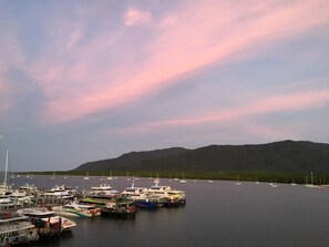 A marina with various boats docked, a mountainous backdrop, and a clear sky. - Cairns Private Apartments (Cairns)