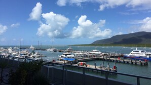 A marina with various boats docked, a pier, and a mountainous backdrop. - Cairns Private Apartments (Cairns)