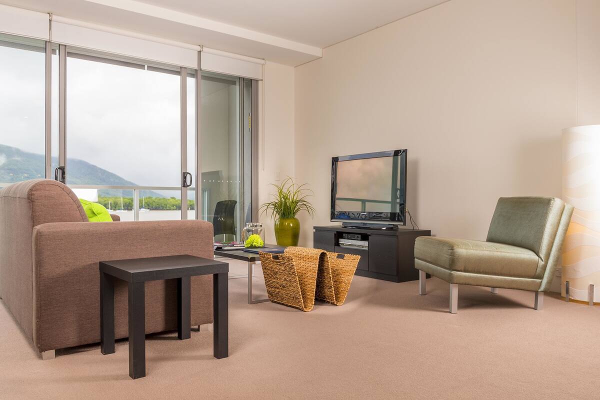 A modern living room with a sofa, armchair, and a flat-screen TV.
