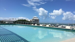 A swimming pool with a clear blue sky and clouds in the background. - Cairns Private Apartments (Cairns)