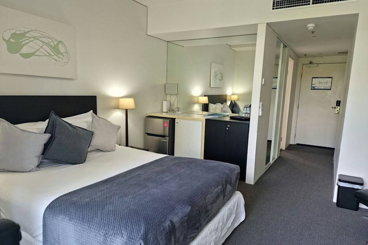 A hotel room with a bed, bedside tables, a desk, and a mirror.